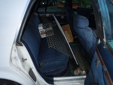 2001 Ford Crown Victoria - Car interior with blue seats, loaded with metal mesh, boxes, and other items.