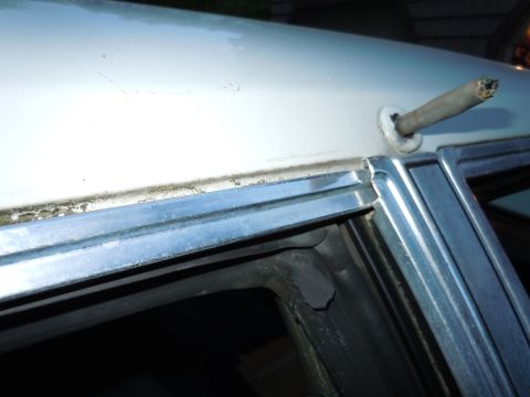 2001 Ford Crown Victoria - Close-up view of the roofline and window trim on a white vehicle, showing a metal rod extending from the roof.