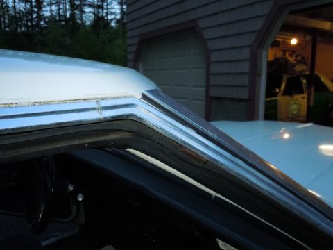 2001 Ford Crown Victoria - Detail of car's roof trim and window seal, with garage and vehicles visible behind.