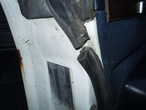 2001 Ford Crown Victoria - The door seal is broken and detached, revealing rust on the vehicle's interior panel.