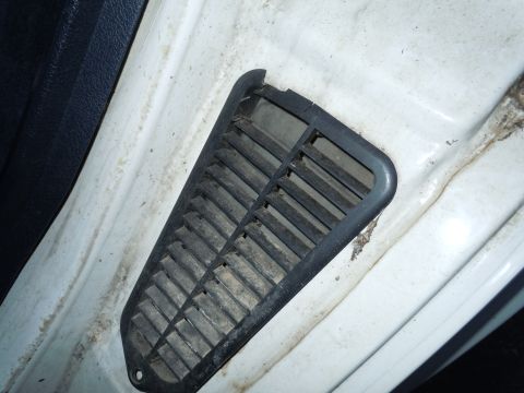 2001 Ford Crown Victoria - Close-up of a dusty interior vent on a white car's door frame.