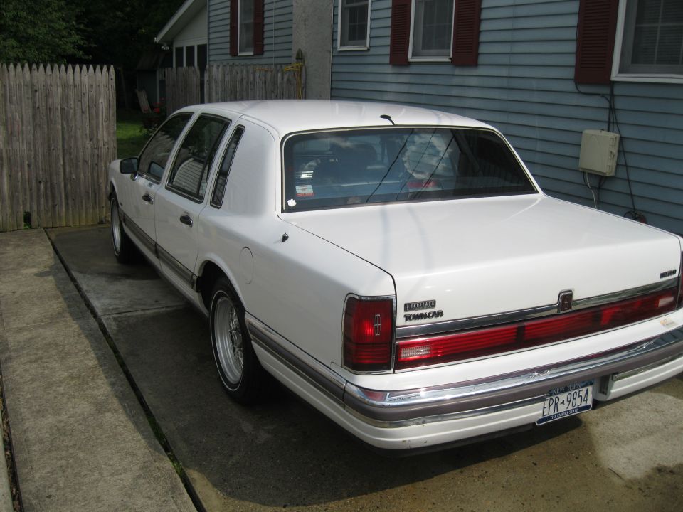 White Lincoln Town Car parked in driveway, rear view. License plate EPR-9854
