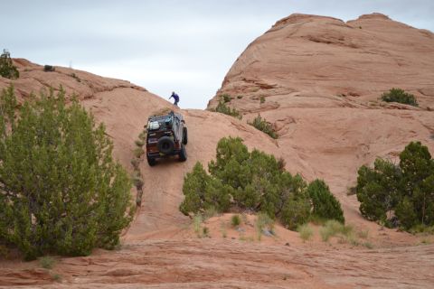 1986 Ford Bronco II - An off-road vehicle navigates a challenging rocky terrain, with a person observing from above.