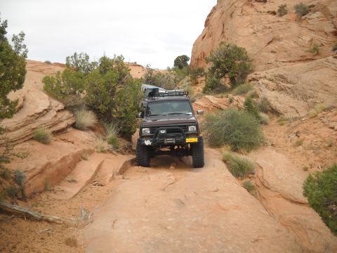 1986 Ford Bronco II - A 1986 Ford Bronco II navigates a challenging rocky path in a desert landscape.