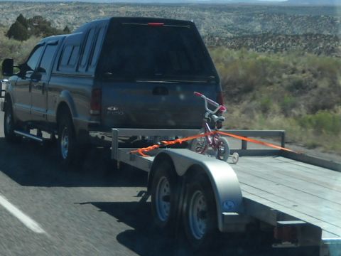 1986 Ford Bronco II - A Ford F-250 Super Duty pickup truck tows a trailer with a bicycle on a highway.