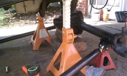 1990 Ford Bronco - Vehicle's undercarriage and suspension components are supported by jack stands during maintenance.