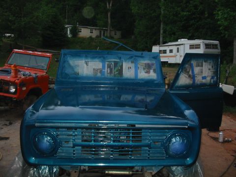 1969 Ford Bronco - A blue Ford Bronco is being painted, with another orange Bronco visible behind it.