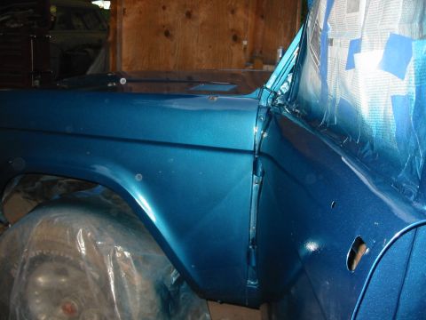 1969 Ford Bronco - A blue 1969 Ford Bronco is being worked on in a garage, with masking tape covering parts of the windshield.
