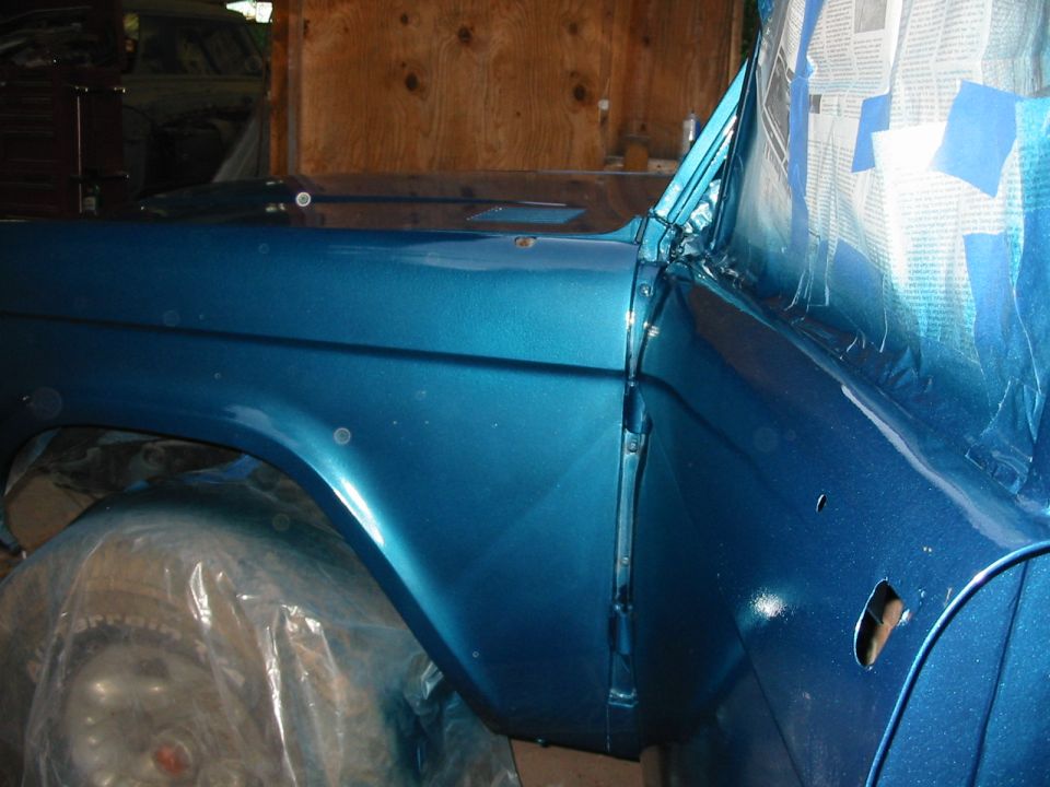 Blue 1969 Ford Bronco fender and door panel, partially masked for painting