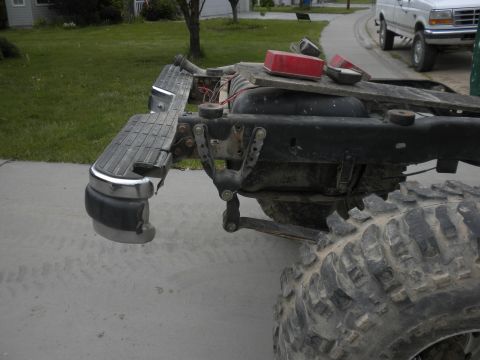 1989 Ford Bronco - Close-up of a truck's rear frame and suspension system, with another vehicle in the background.