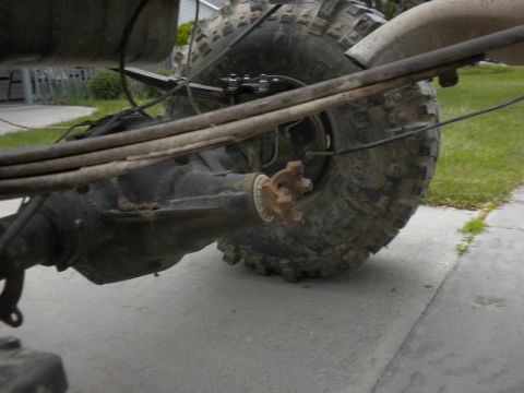 1989 Ford Bronco - Close-up view of the rear axle and suspension system, large off-road tires and leaf springs.