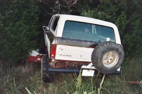 1978 Ford Bronco - Rear view of a 1978 Ford Bronco with a spare tire, parked in a grassy, wooded area.
