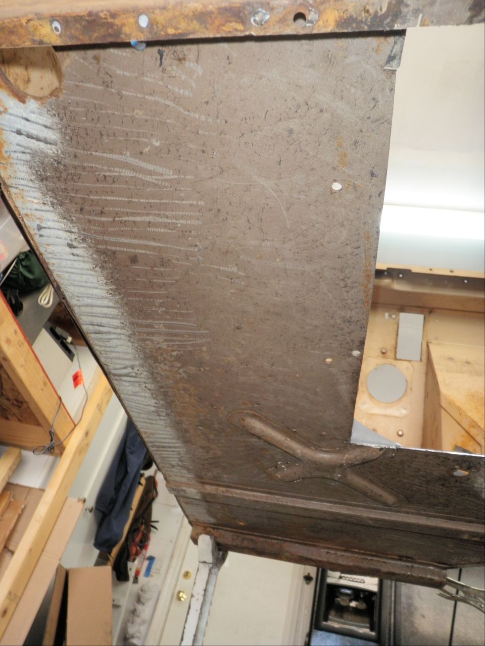 Rusted metal panel with horizontal scratch marks and a central raised brace