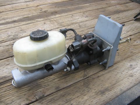 1978 Ford Bronco - This brake master cylinder assembly features a plastic reservoir and is shown on a wooden surface.