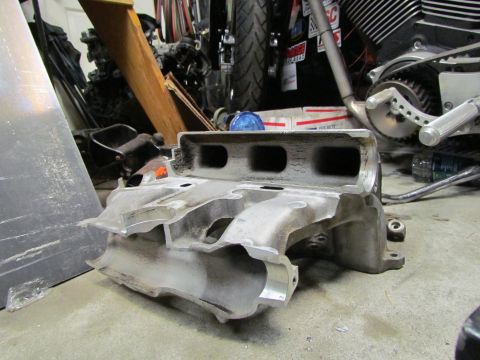 1995 Ford Probe - An aluminum intake manifold is shown in a workshop setting, with a motorcycle and other parts in the background.