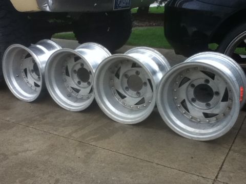 2006 Ford E350 - A set of five aluminum alloy wheels are displayed on a concrete driveway.