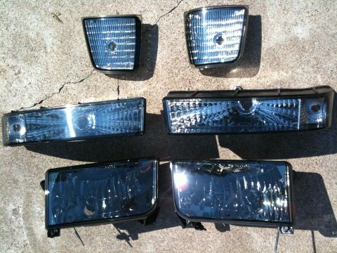 1996 Ford Bronco - A collection of vehicle headlights and corner lights are laid out on a concrete surface.