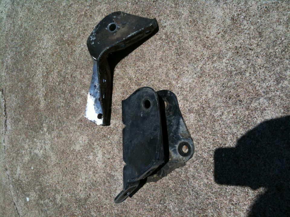Two black metal brackets on concrete. Text reads SUPERMOTORS.NET