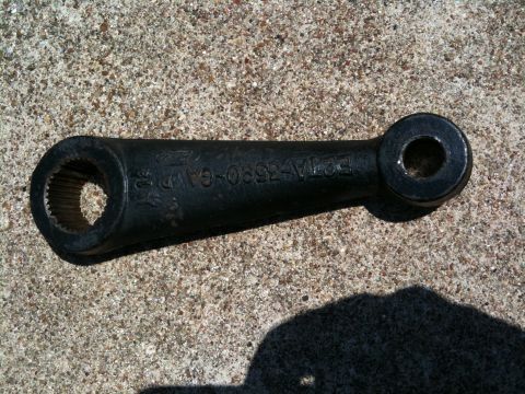 1996 Ford Bronco - A close-up of a steering linkage arm, likely a replacement part, rests on a concrete surface.