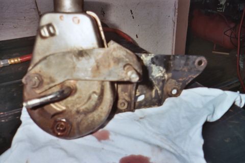 1978 Ford Bronco - Close-up of a used power steering pump and its bracket, showing signs of wear and fluid leakage.