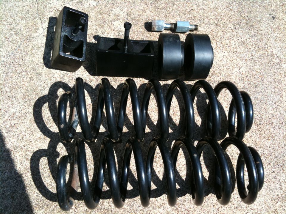 Suspension lift kit components including coil springs and blocks laid out on concrete