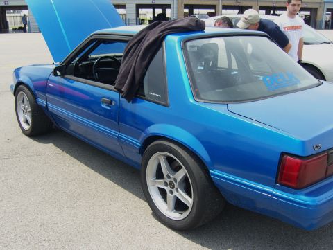 2007 Ford Mustang - A blue coupe sits on pavement with its hood open, a black jacket draped over the roof.