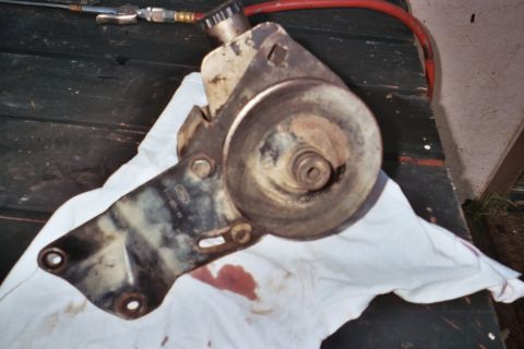 1978 Ford Bronco - A used Ford power steering pump bracket with pulley and reservoir is shown on a white cloth.