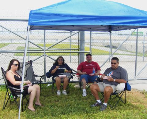 2007 Ford Mustang - People relax under a canopy near a fence, with one person wearing a Mustang shirt.
