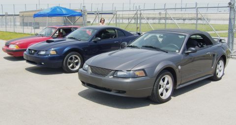 2007 Ford Mustang - Three Ford Mustangs are parked in a line, with a gray convertible in the foreground.
