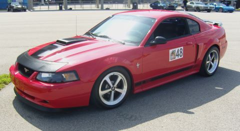2007 Ford Mustang - Red 2007 Ford Mustang coupe with racing decal on the door parked outdoors.
