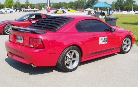 2007 Ford Mustang - A red Ford Mustang is parked at an event with other cars in the background.