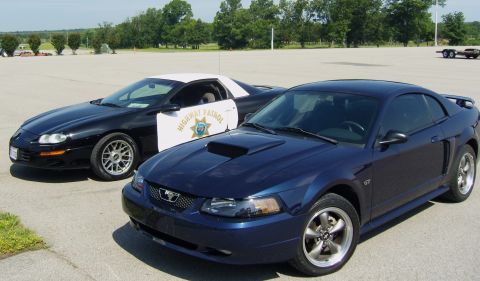 2007 Ford Mustang - A blue Ford Mustang GT is parked next to a black and white Highway Patrol car.
