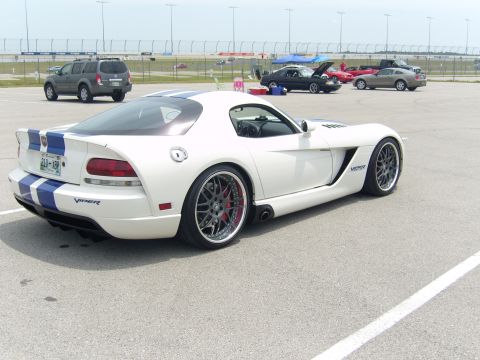 2007 Ford Mustang - A white Dodge Viper with blue stripes is parked on a track with other vehicles in the background.