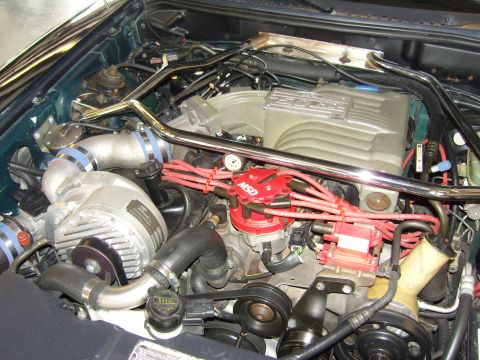 2007 Ford Mustang - Close-up view of a modified engine bay, a supercharger and performance ignition components.