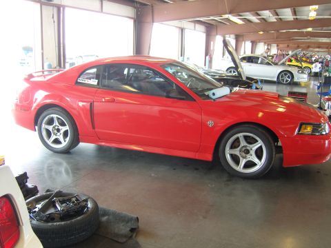 2007 Ford Mustang - A red sports car is parked indoors, with other vehicles visible in the background.