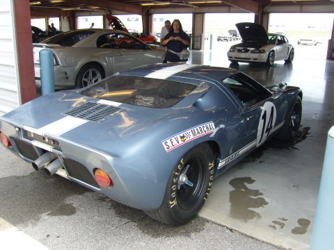 2007 Ford Mustang - A blue race car with white stripes and the number 14 is parked in a garage bay, with other vehicles visible in the background.