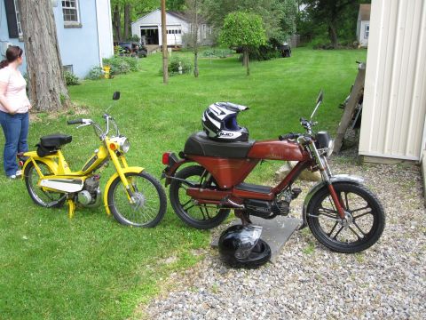 1981 Garelli Rally Sport - A yellow moped and a maroon moped are parked outside a residential building.