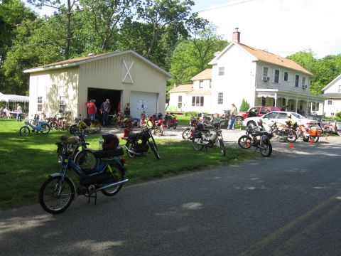 1981 Garelli Rally Sport - A gathering of vintage mopeds and motorcycles is displayed outdoors on a sunny day.