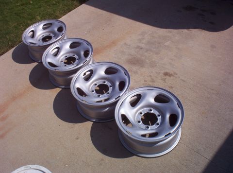 1988 Ford Bronco - Four steel wheels are lined up on a concrete driveway.