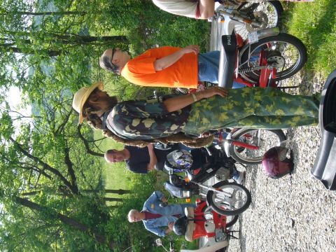 1981 Garelli Rally Sport - A group of people stand around several parked mopeds in a casual outdoor setting.