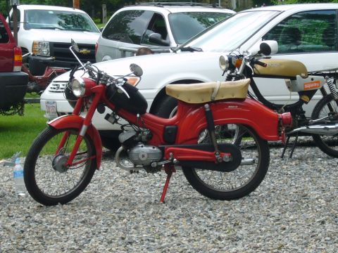 1981 Garelli Rally Sport - A red moped with a tan seat is parked on a gravel surface, with other vehicles in the background.