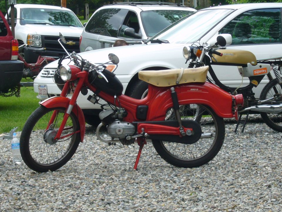 red moped parked next to a white SUV and another moped
