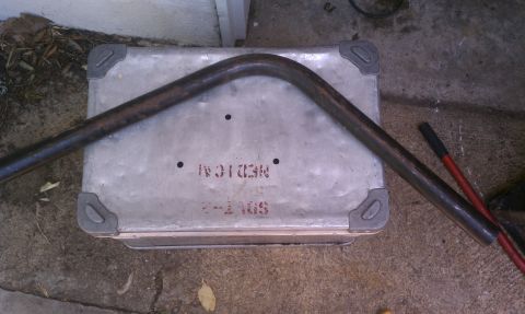 1990 Ford Bronco - Metal box with stenciled text and a bent pipe, possibly a part or tool.