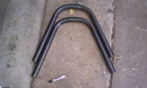 1990 Ford Bronco - Two bent metal tubes are shown on a concrete surface, with a marker pen also visible.