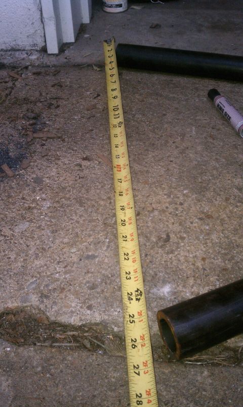 1990 Ford Bronco - A tape measure lies on a concrete floor, alongside two black metal pipes, with text from a website visible.