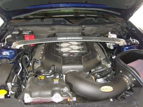 2007 Ford Mustang - The engine bay of a blue Ford Mustang, showing a 5.0L V8 engine with an aftermarket air intake and strut tower brace.
