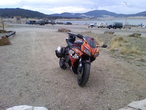2006 Honda CBR-RR - Sport motorcycle parked on gravel with a lake and mountains in the background.
