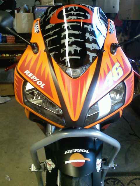2006 Honda CBR-RR - Front view of an orange and black motorcycle with racing decals and a gun graphic on the windshield.