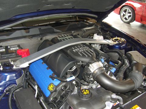 2007 Ford Mustang - Engine bay of a blue Ford Mustang, identified as a 2007 model, with a red Mustang visible in the background.