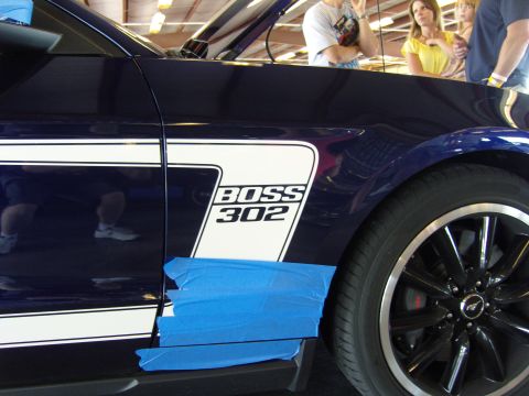 2007 Ford Mustang - Side view of a dark blue Ford Mustang Boss 302 with white racing stripes and blue tape on the lower body panel.
